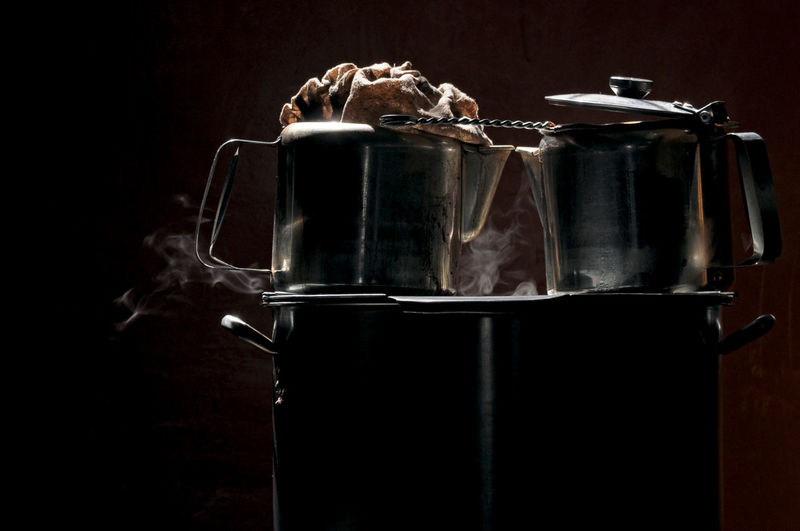 Low key photo of  coffee and teapots on a large pot to boiling water