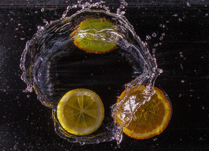 Close-up of lemon slice in water against black background
