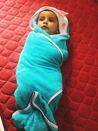 High angle view of baby wrapped in towel lying on bed at home