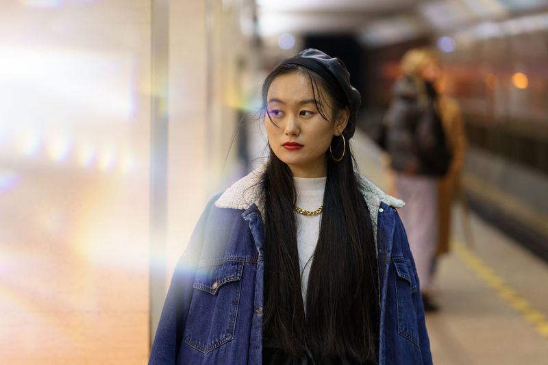 Millennial japanese girl in trendy leather beret and coat wait for train at subway underground