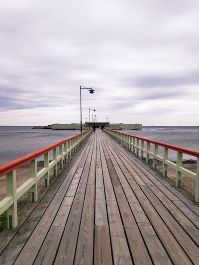Empty wooden pier over sea against sky