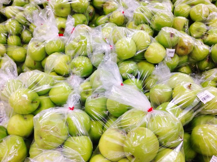 Full frame shot of granny smith apples packed in plastic at market for sale