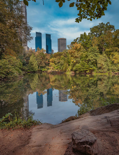 Reflection of trees and buildings in lake against sky