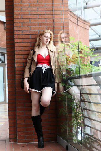 Full length of woman standing against brick wall