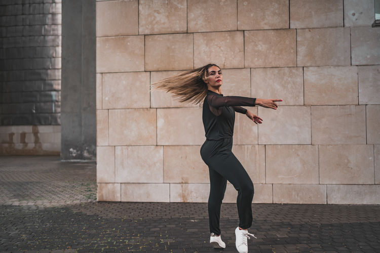 Beautiful young dancer looking away while dancing on the urban city street. person