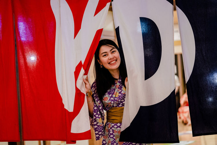 Portrait of smiling young woman peeking through fabric