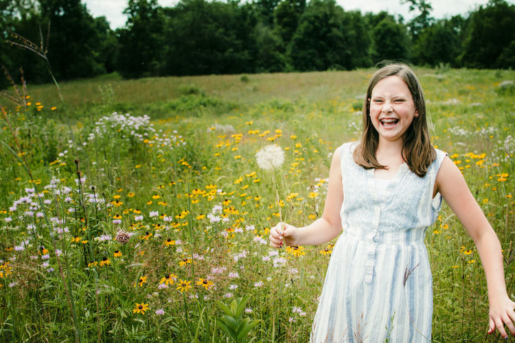 Smiling young woman with flower petals on field