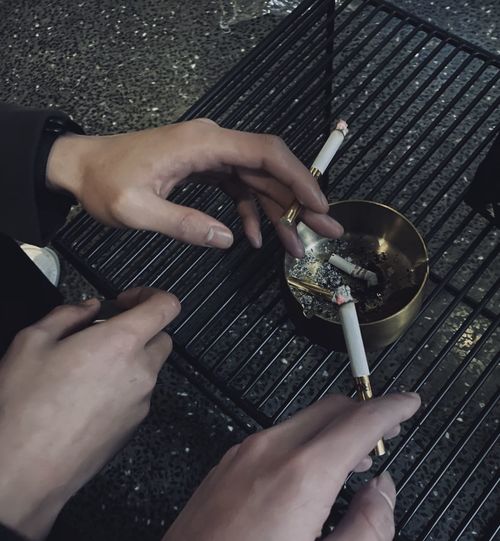 Cropped hands of friends smoking cigarette in home