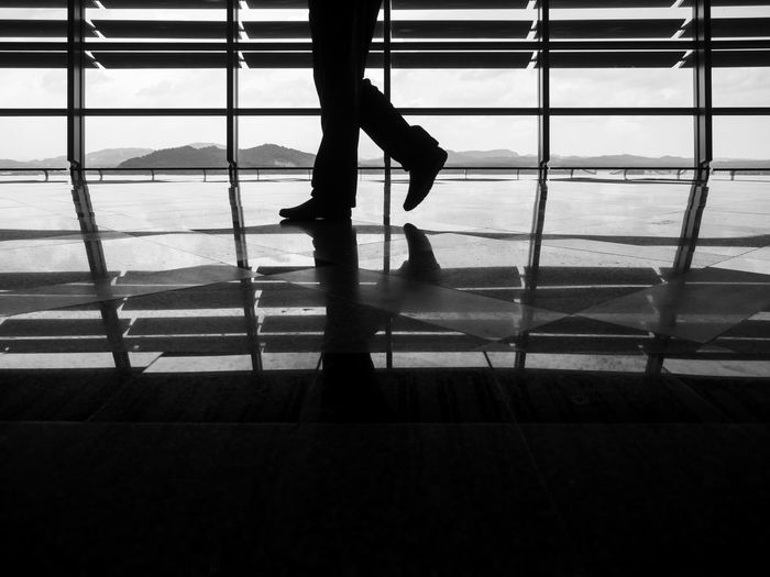 Low section of silhouette man walking on shiny floor