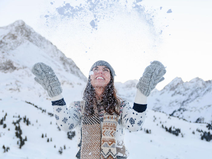 Portrait of a woman in winter clothes throwing snow in the air. smiling, happy.
