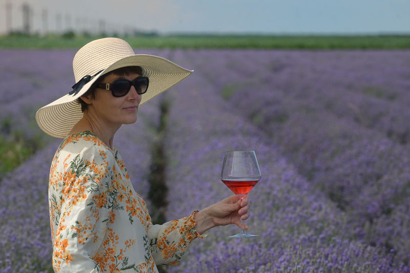 Woman with rose wine in lavender summer field