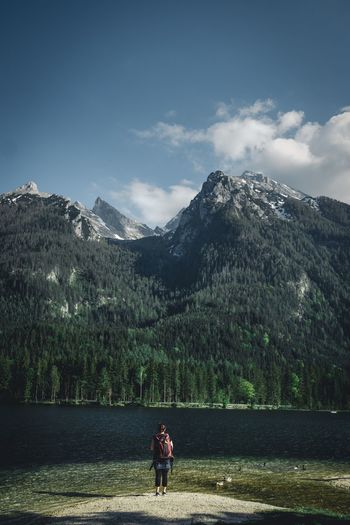 Rear view of women standing by lake against mountain