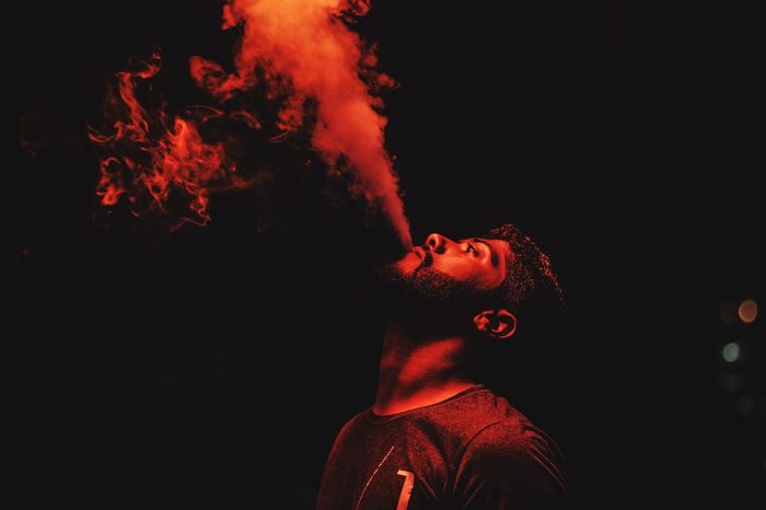 Man smoking against black background