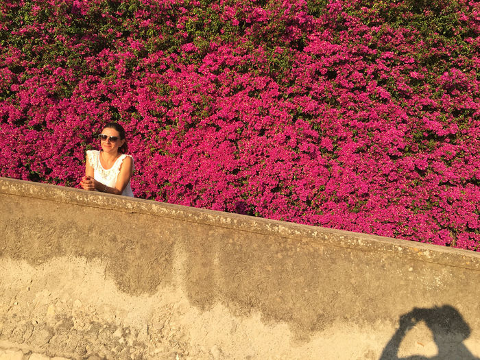 Portrait of young woman against pink flowers
