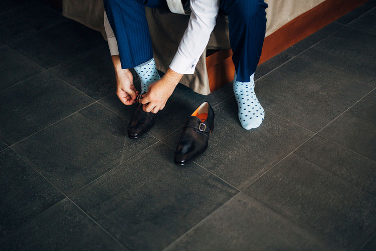 Low section of man wearing shoes at home