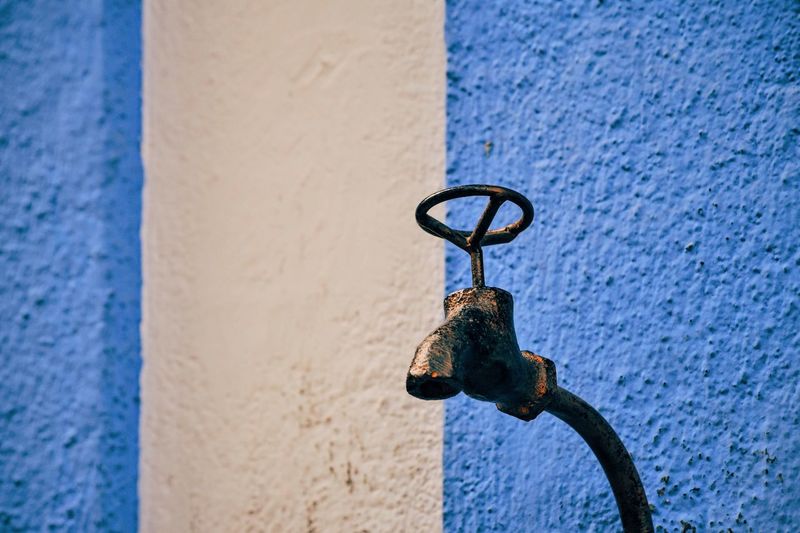 Low angle view of faucet against blue wall