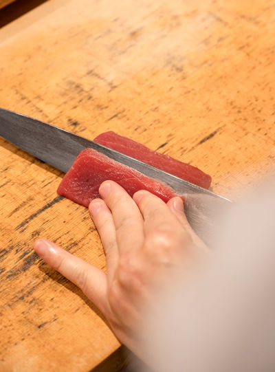 Cropped hand of person holding knife on table