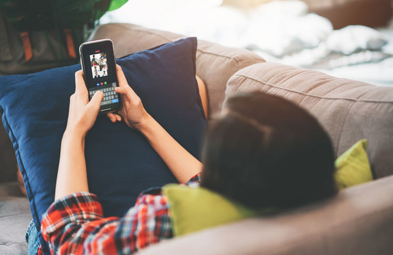 Midsection of man using mobile phone on sofa