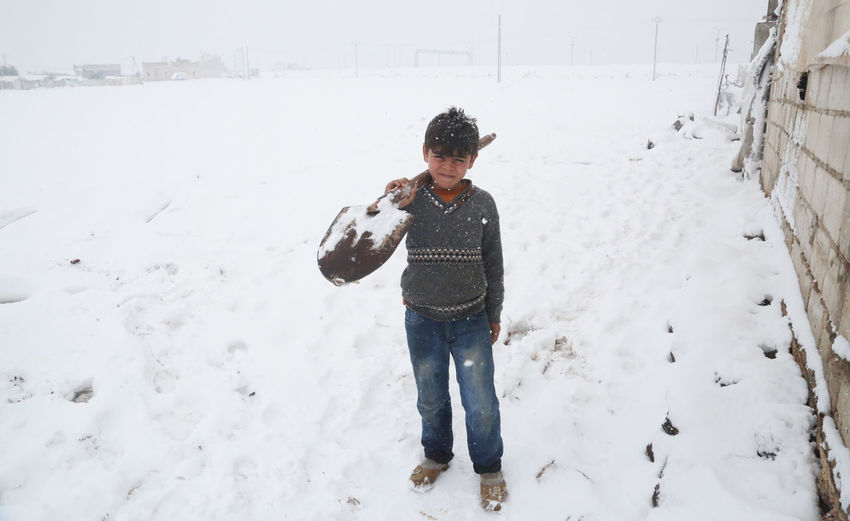 Full length of boy standing on snow covered field