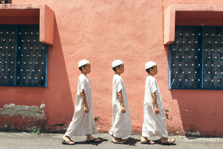 Side view of brothers in traditional clothing walking by building