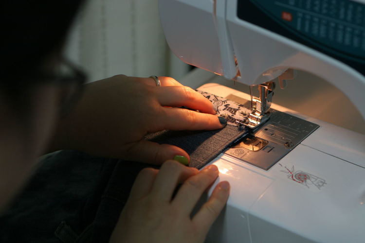 High angle view of woman working with fabric on sewing machine