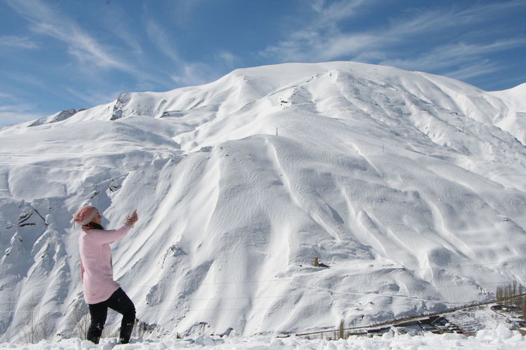 Woman standing against snow capped mountain against sky
