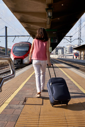 Woman walking with a suitcase in a train station