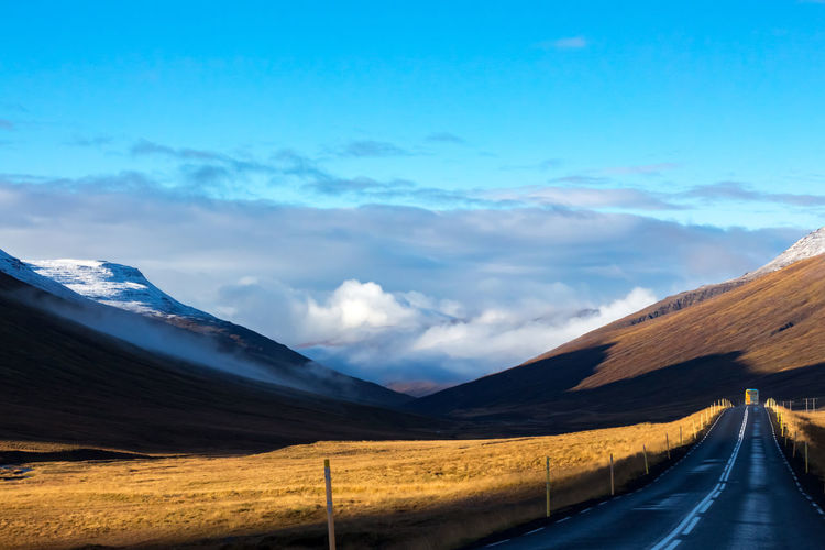 Road towards mountains against blue sky