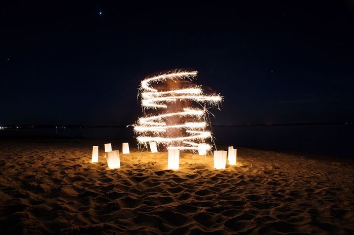 Light paintings with lamps on beach against clear sky