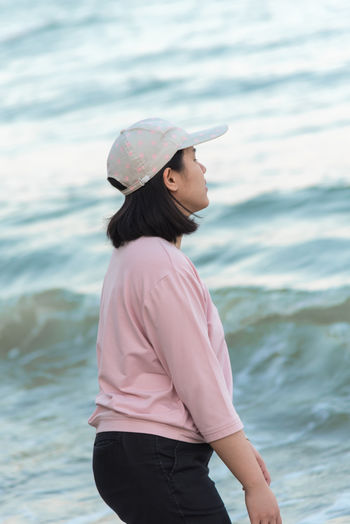 Young woman wearing hat standing in sea
