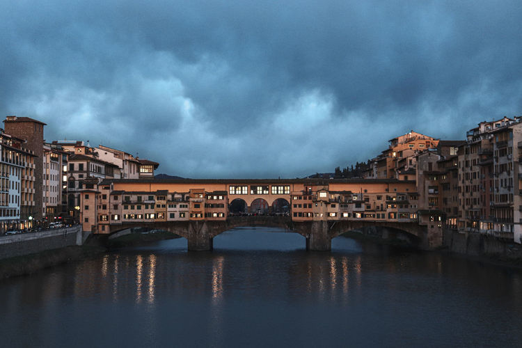 Arch bridge over river against sky in city