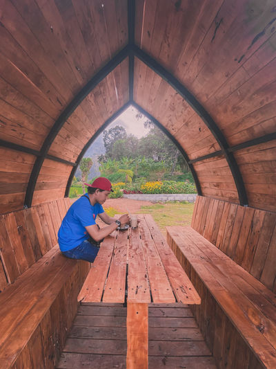Man sits under a wooden pavilion