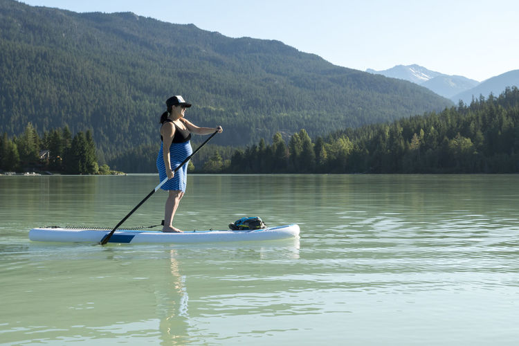 Full length of boy standing on lake against mountains