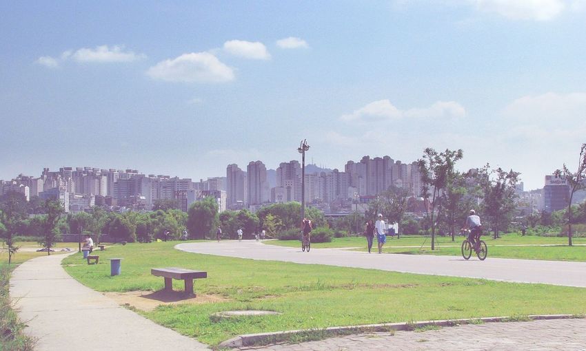 People enjoying at park by city against sky
