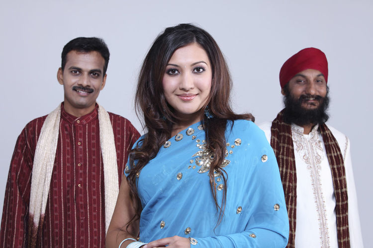 Portrait of friends standing in traditional clothing against white background