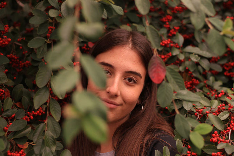 Portrait of smiling woman standing by berries on tree