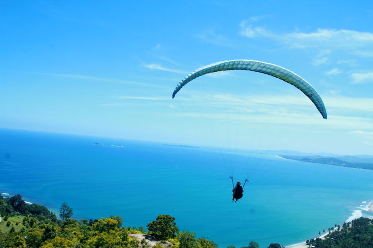 Man paragliding over sea against sky