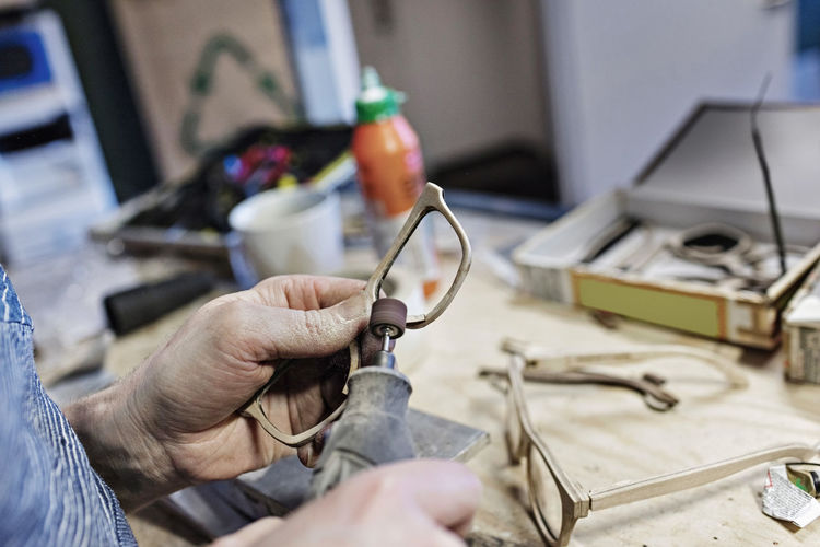 Cropped image of owner making eyeglasses with work tool at workshop