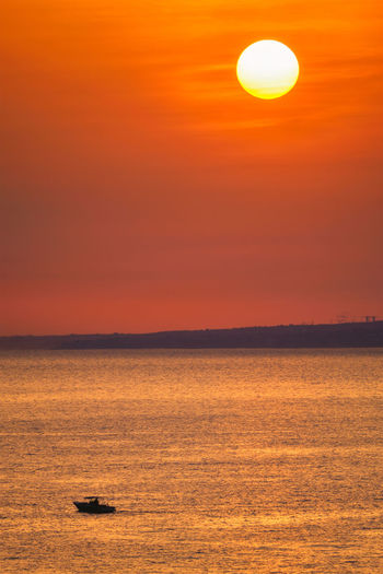 Scenic view of sea against orange sky