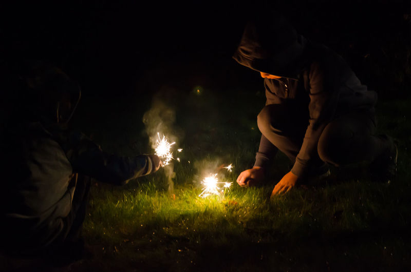 Boys playing with sparklers at night