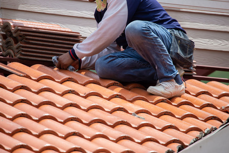 Low section of man working on roof