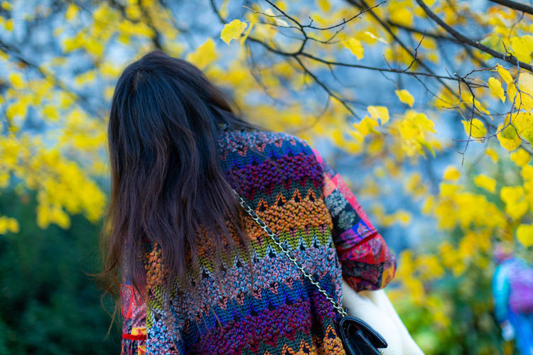 Rear view of woman standing against yellow during autumn