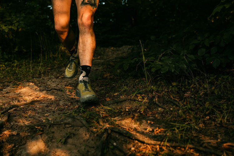 Low section of man running in forest