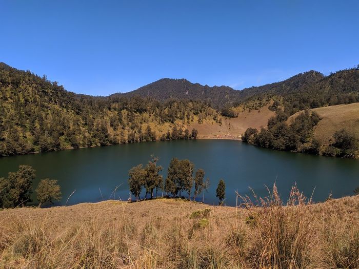 Scenic view of lake and mountains against clear blue sky