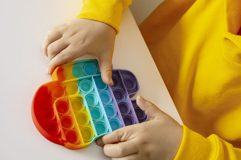 Little boy plays with rainbow pop it fidget toy. antistress children game. children's trendy toy