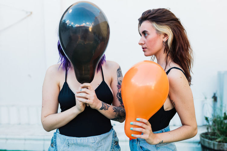 Lesbian couple holding balloons while standing outdoors
