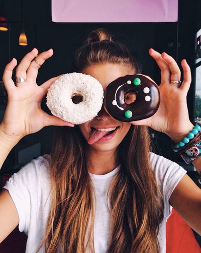 Close-up portrait of smiling young woman holding donuts