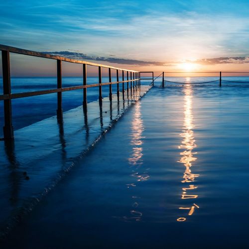Pier on sea against sky during sunset