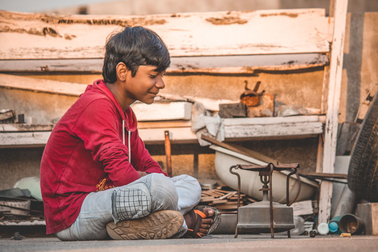 Side view of boy sitting with old stove 