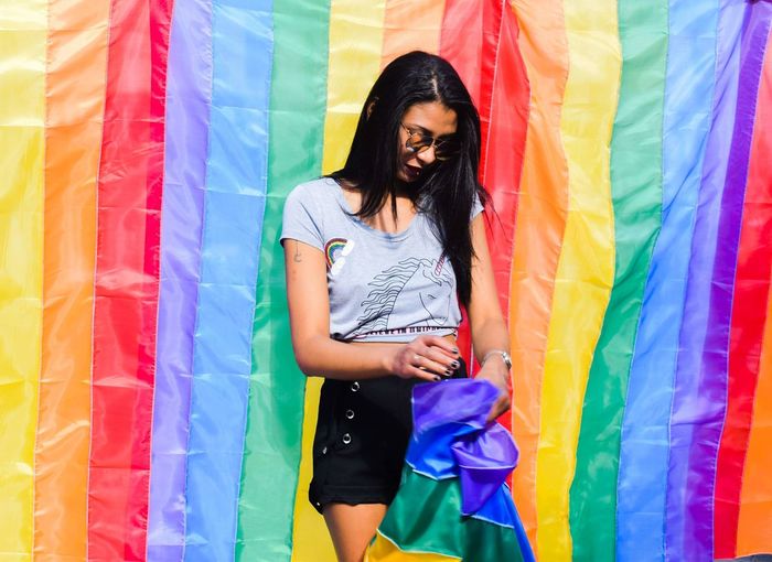 Young woman standing against rainbow flag